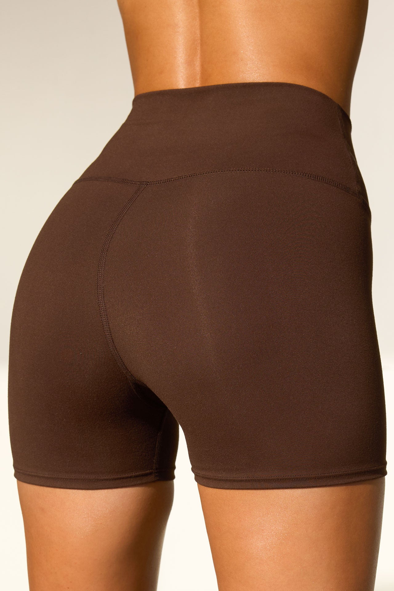 Close up detail back view of model from the waist down wearing the soft stretchy high-waisted sueded umber The Body Short with a wide waistband