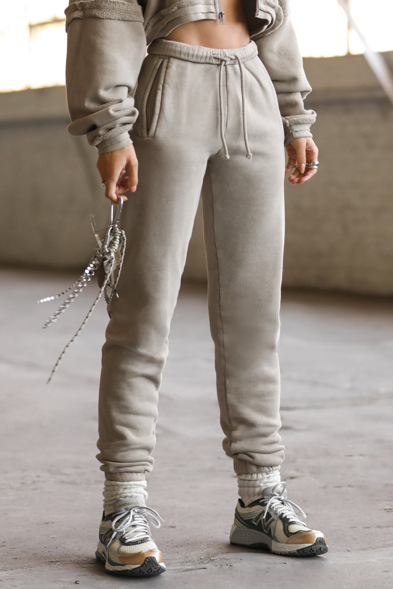 Front view of model from the waist down posing in the tapered sand french terry Empire Jogger with side pockets and an elastic waistband and ankle cuffs