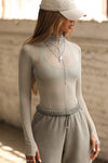 Front view of model posing in the fitted and sheer dew mesh Exposed Seams Long Sleeve top with a mock neckline and exposed seam details