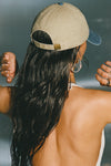 Back view of model wearing the six-panel khaki with vintage blue brim Official Cap with a curved brim and adjustable strap