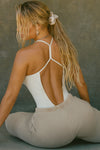 Back view of model posing in the fitted chalk modal Open T-Back Cami with an open t-back design