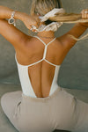 Back view of model posing in the fitted chalk modal Open T-Back Cami with an open t-back design