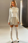 Full body front view of model posing in the mini dew mesh Wrap Skirt with an adustable waist tie