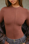 Front view of model posing in the form fitting oxblood flexrib Invisible Zip Long Sleeve top with a 3/4 front invisible zipper and a crew neckline