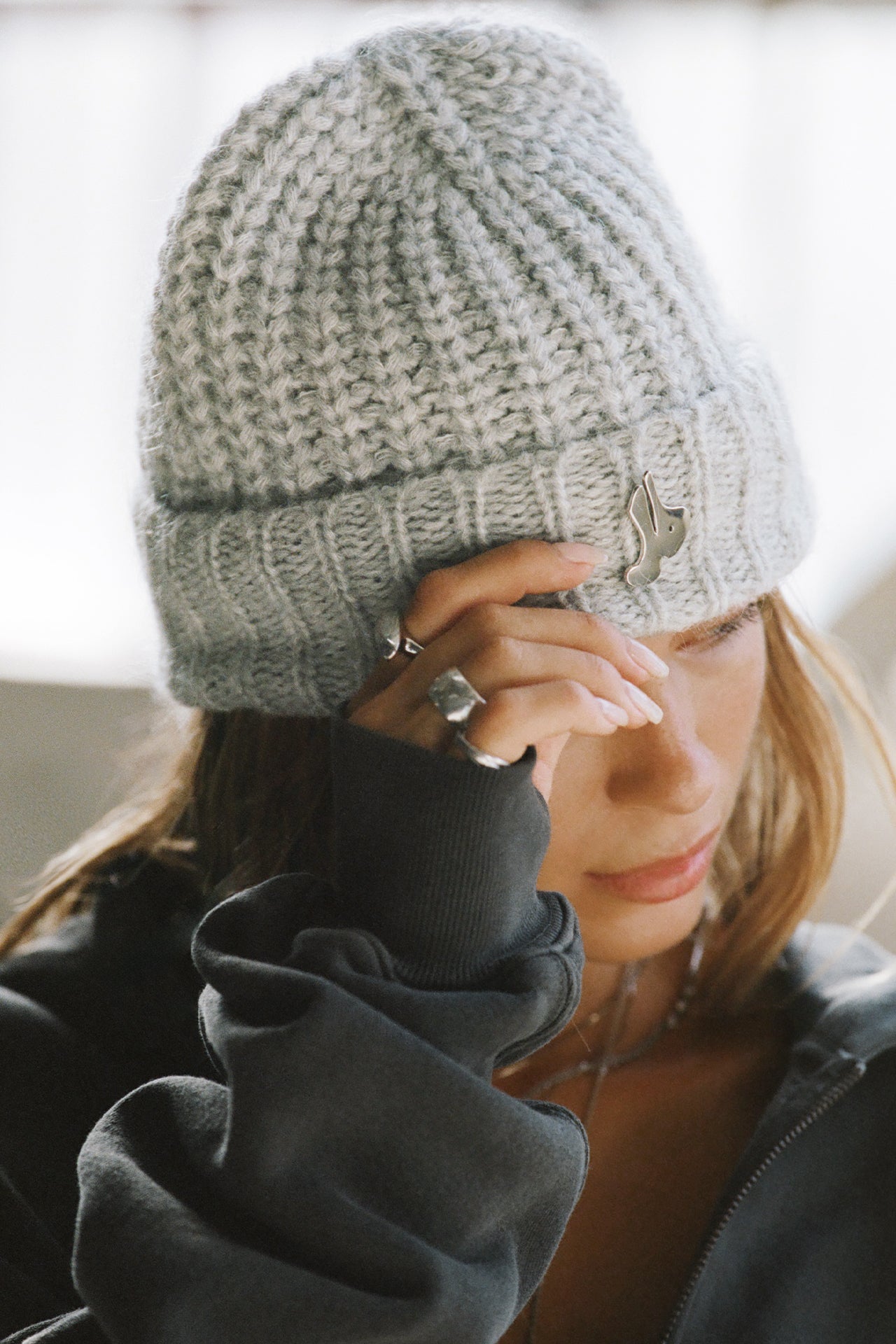 Front view of model posing in the soft and warm sterling Knit Beanie that has removable custom JOAH BROWN pin.