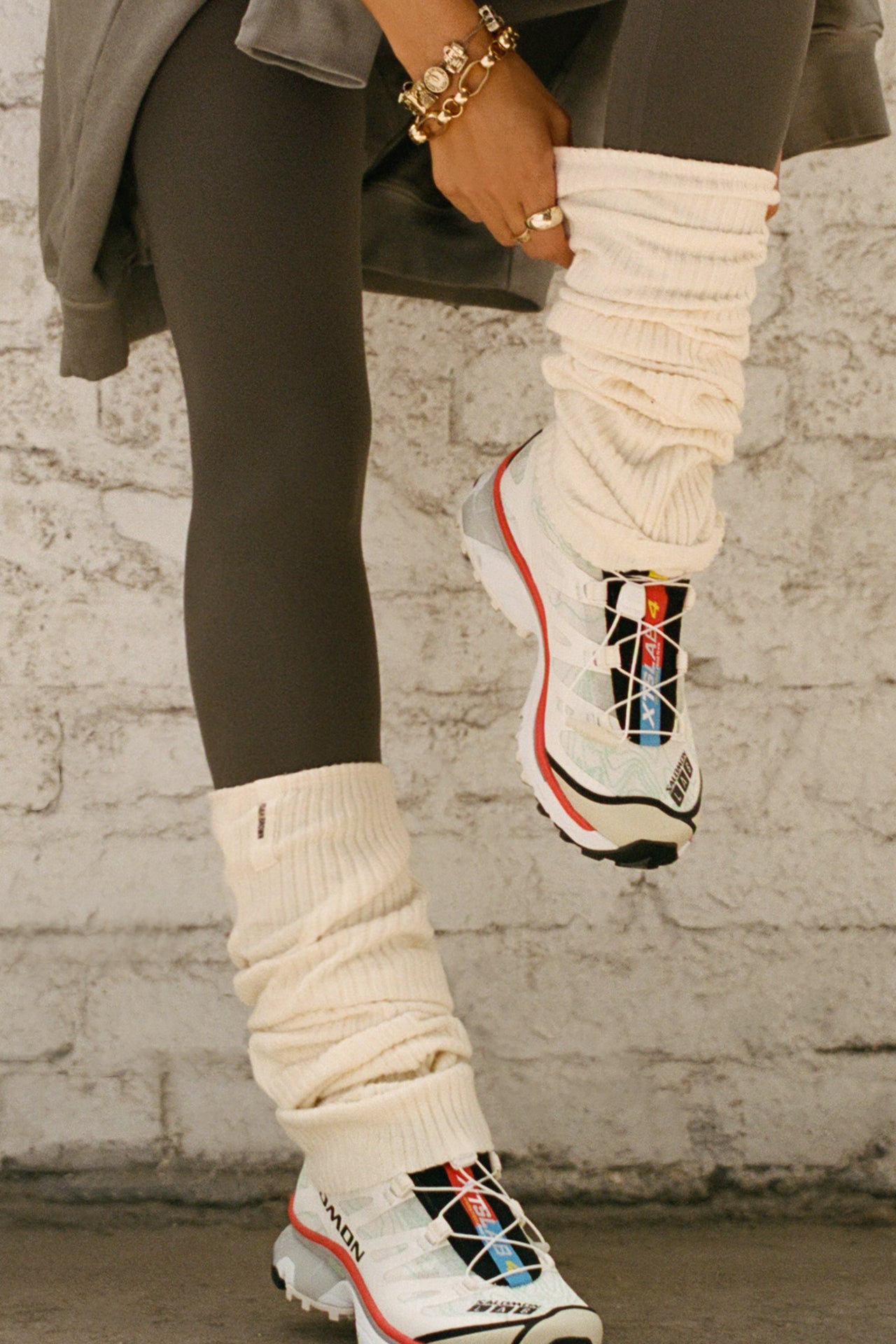 Front view of model adjusting the slouchy, pull on natural luxe knit Leg Warmers that can be worn pulled up on scrunched down