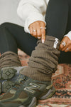 Close up view of model adjusting the slouchy, pull on army luxe knit Leg Warmers that can be worn pulled up on scrunched down