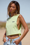 Side view of model posing in the relaxed fit melon cotton Cut Off Boyfriend Tank with low cut armholes, a crew neckline and a joah brown logo patch at the upper left chest