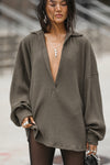 Side view of model posing outside in the oversized army luxe knit Deep V Pullover with a plunging collared neckline and dropped shoulders