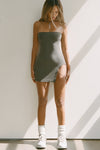 Full body front view of model posing in the fitted and mini mineral flexrib Curve Hem Tube Dress with a high side split and curved hem