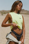 Front view of model posing in the relaxed fit melon cotton Cut Off Boyfriend Tank with low cut armholes, a crew neckline and a joah brown logo patch at the upper left chest