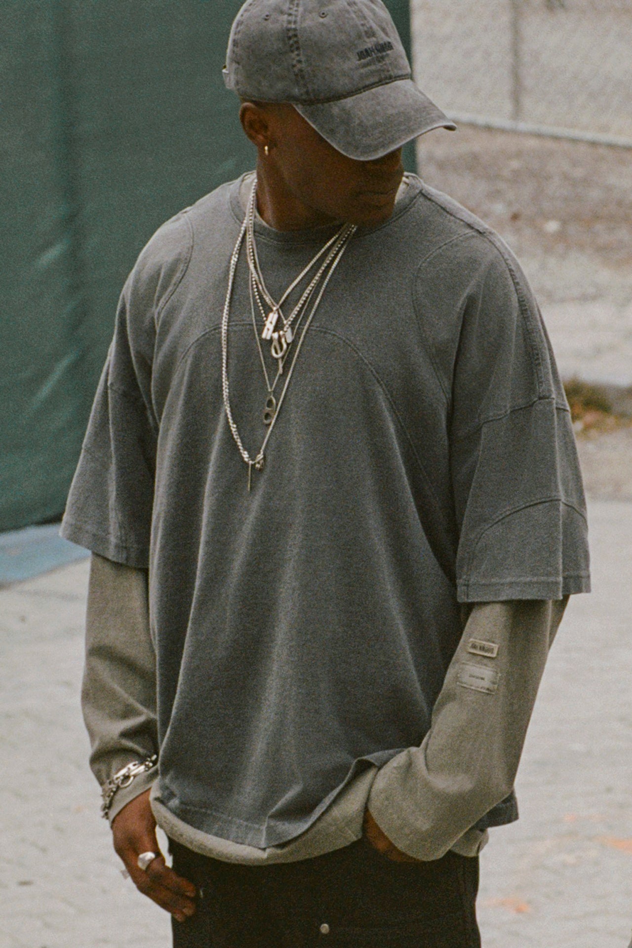 Front view of male model posing outside on a sidewalk wearing the oversized washed black cotton Original Graphic Tee with panel details 