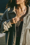 Close up front view of model posing in the relaxed fit fern sherpa Oversized Button Down shirt jacket with a classic collar, front button closures and contrasting fabric details.