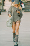 Full body front view of model walking in the slouchy, army luxe knit Leg Warmers that can be worn pulled up or scrunched down