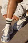 Close up front view of model posing in the crew style ribbed soft moss Mini Stripe Sock