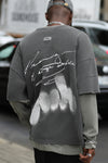 Back view of male model posing in the oversized washed black cotton Original Graphic Tee with panel details and custom screen print graphic “dreaming of a strange world” on the back