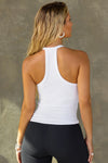 Back view of model posing in the fitted stretchy white flexrib V Neck Racerback Tank with a narrow racerback silhouette and thin straps