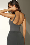 Back view of model posing in the fitted and stretchy smoke flexrib Low Back Scoop Tank with a u-neckline, thin straps and a  low scoop back.