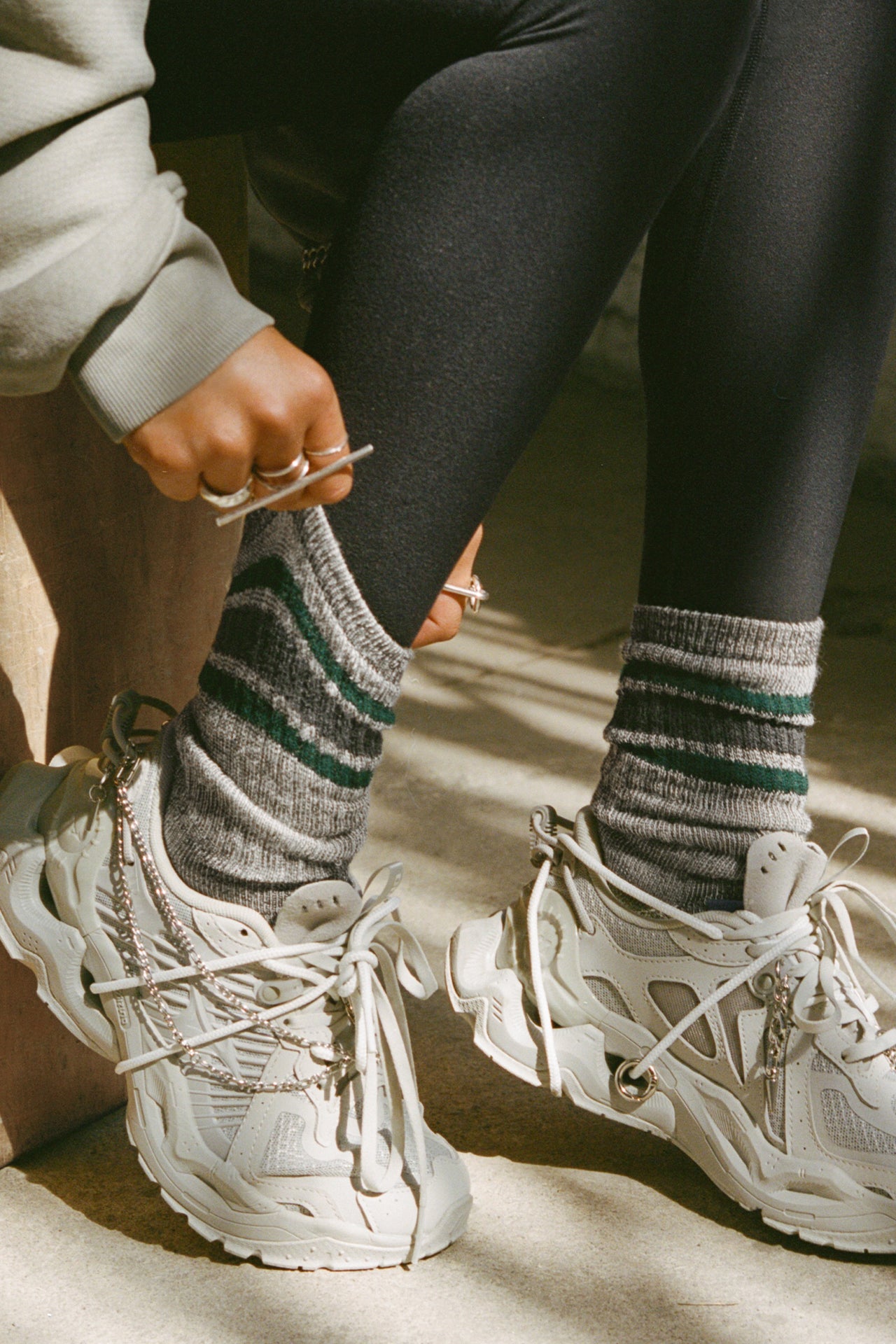 Close up side view of model adjusting the crew-style ribbed and soft heathered charcoal Merino Stripe Sock