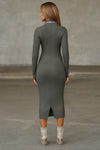 Full body back view of model posing in the fitted mineral rib Mock Neck Midi Dress with a mock turtleneck neckline, long sleeves, quarter zip back and a mid-calf length