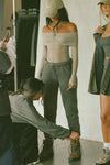 Full body front view of model posing in the fitted dew mesh Off The Shoulder Long Sleeve top with a folded off-the-shoulder neckline and thumbholes in the sleeves