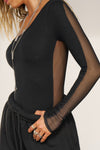 Close up side view of model posing in he fitted black flexrib One Shoulder Long Sleeve top with an asymmetrical neckline, flexrib front and mesh back.