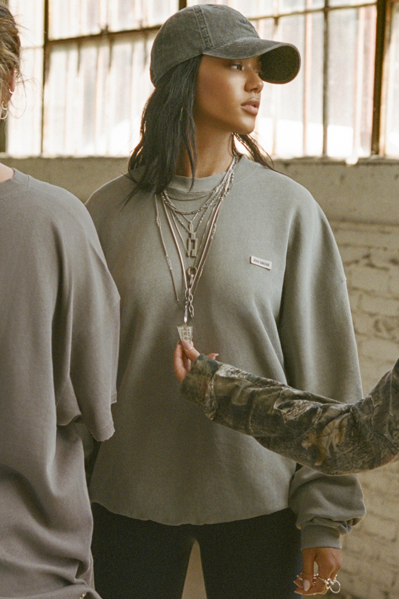 Full body front view of model posing in the oversized vetiver french terry Classic Crew Pullover sweatshirt with a crew neckline and joah brown logo patch sewn on the upper left chest