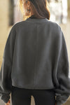 Back view of model posing in the relaxed fit washed black french terry Oversized Crew Pullover sweatshirt with dropped sleeves and a ribbed crew neckline