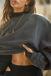 Detail front view of model posing in the relaxed fit washed black french terry Oversized Crew Pullover sweatshirt with dropped sleeves and a ribbed crew neckline