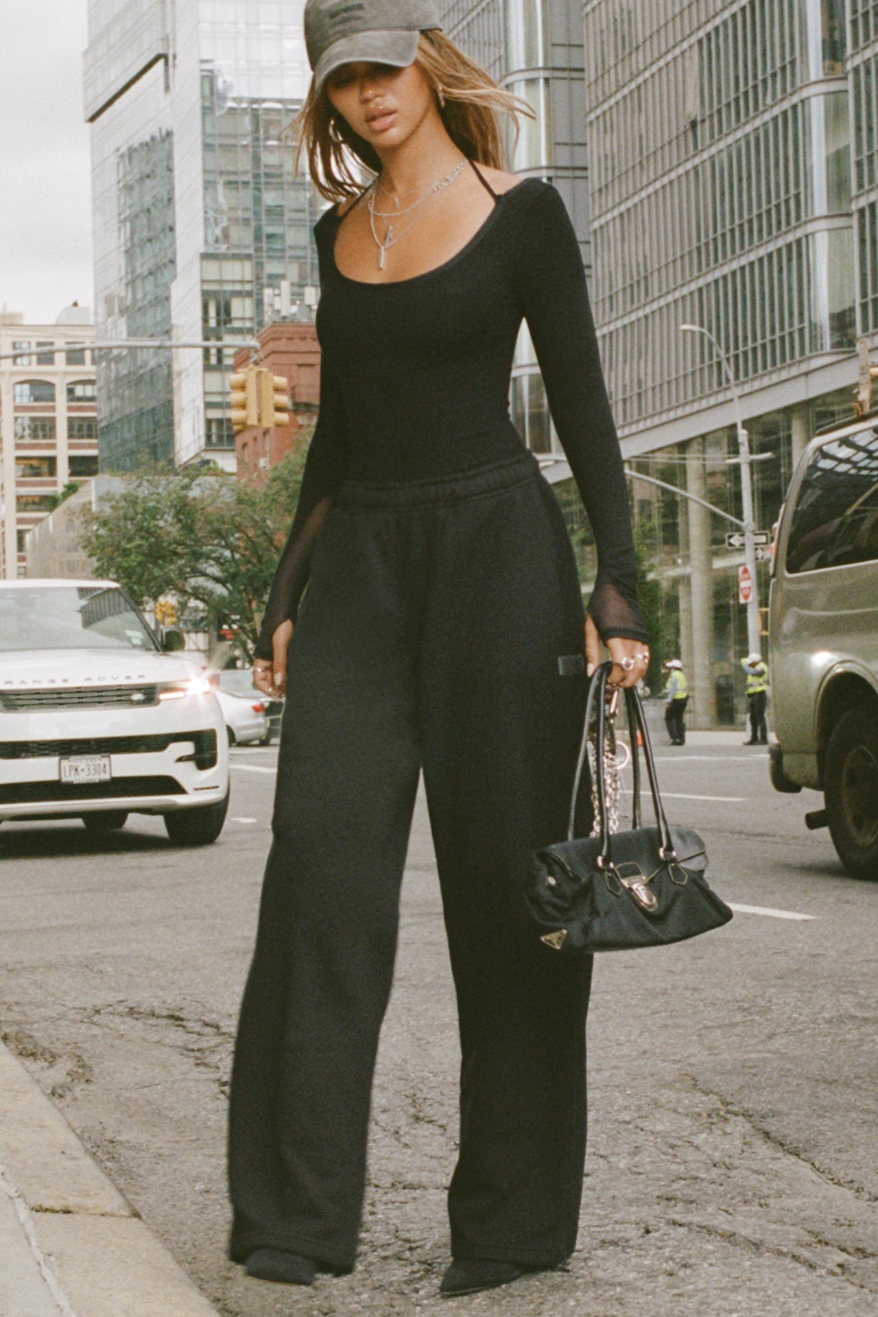 Full body front of model posing in the street wearing the relaxed fit black french terry Oversized Straight Leg Jogger with an elastic waistband, hidden drawstring, pocket details. and adjustable cinching at the ankle cuffs