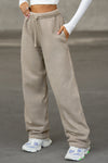 Front view of model from the waist down posing in the relaxed fit sand french terry Oversized Straight Leg Jogger with an elastic waistband, hidden drawstring, pocket details. and adjustable cinching at the ankle cuffs