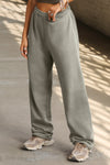 Side view of model from the waist down posing in the relaxed fit vetiver french terry Oversized Straight Leg Jogger with an elastic waistband, hidden drawstring, pocket details. and adjustable cinching at the ankle cuffs