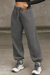 Front view of model from the waist down posing in the relaxed fit washed black french terry Oversized Straight Leg Jogger with an elastic waistband, hidden drawstring, pocket details. and adjustable cinching at the ankle cuffs