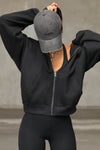 Front view of model posing in the oversized comfortable black french terry Oversized Zip Hoodie with a full length front zip closure, side pockets and thumbholes in the fitted cuffs