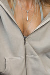 Close up detail front view of the oversized comfortable sand french terry Oversized Zip Hoodie with a full length front zip closure, side pockets and thumbholes in the fitted cuffs