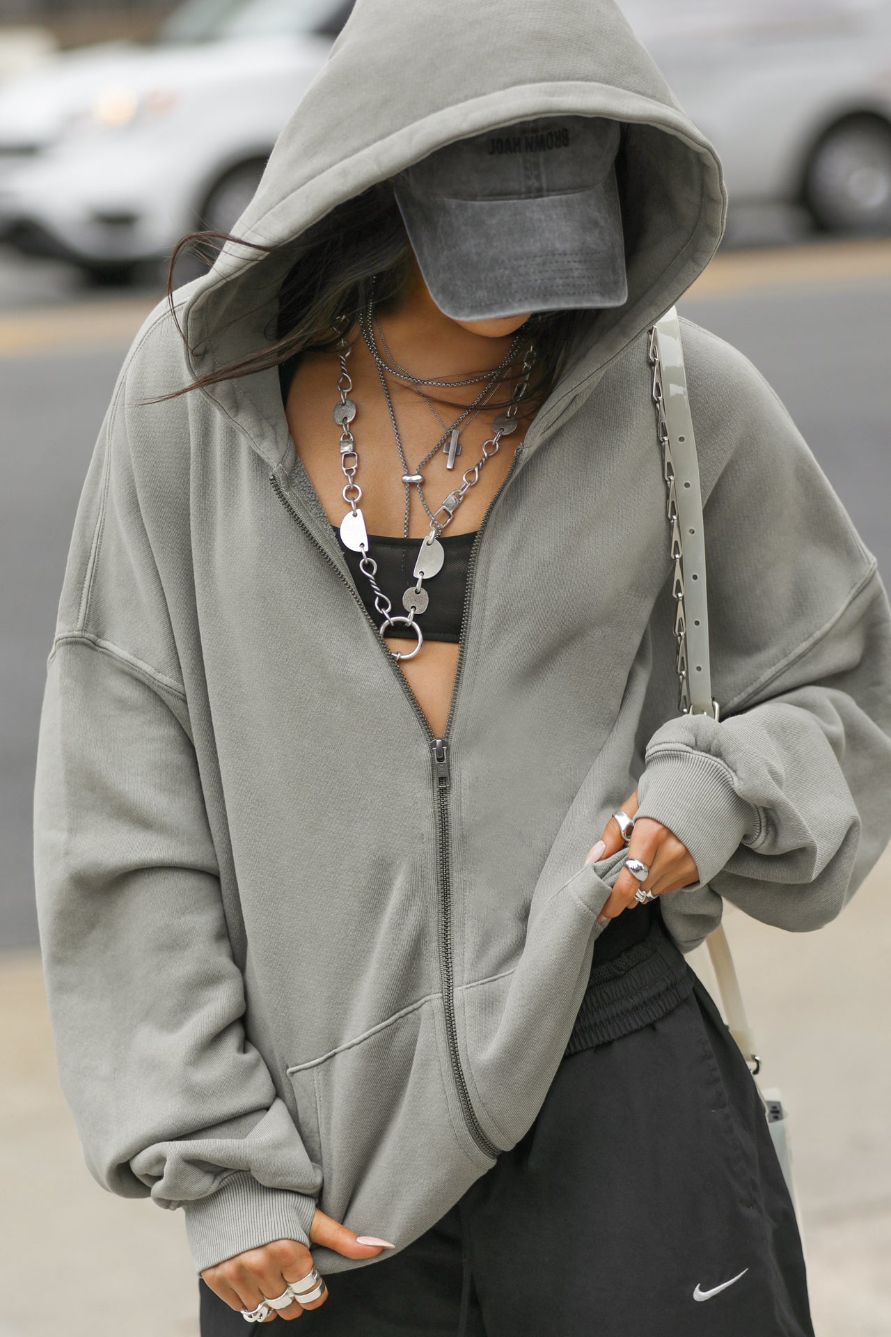 Front view of model posing outside in the street in the oversized comfortable vetiver french terry Oversized Zip Hoodie with a full length front zip closure, side pockets and thumbholes in the fitted cuffs