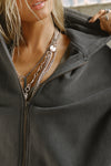 Close up detail front view of model posing in the oversized comfortable washed black french terry Oversized Zip Hoodie with a full length front zip closure, side pockets and thumbholes in the fitted cuffs