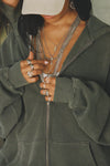 Close up front view of model posing in the oversized comfortable washed sage french terry Oversized Zip Hoodie with a full length front zip closure, side pockets and thumbholes in the fitted cuffs