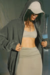 Side view of model posing in the oversized comfortable washed sage french terry Oversized Zip Hoodie with a full length front zip closure, side pockets and thumbholes in the fitted cuffs