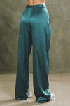 Back view of model from the waist down posing in the soft and smooth classic pleated lagoon silk Relaxed Silk Trouser with a flattering wide leg, zip fly and side pockets.