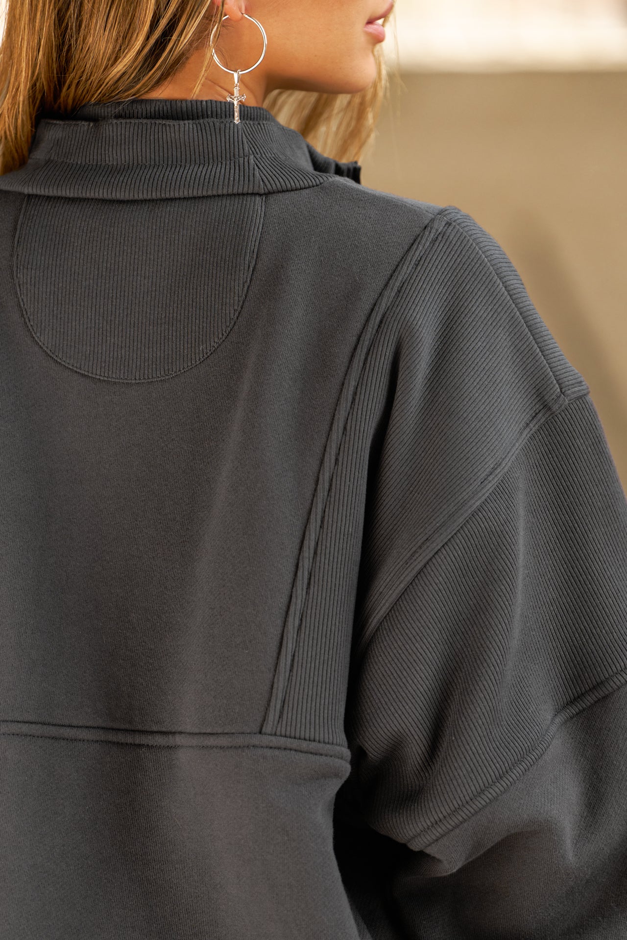 Close up back view of model posing in the oversized comfortable charcoal luxe french terry Retro Half Zip pullover sweatshirt with ribbed panels and accents on the back and sleeves and a high collar