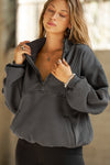 Front view of model posing in the oversized comfortable charcoal luxe french terry Retro Half Zip pullover sweatshirt with ribbed accents on the chest and sleeves, a hidden kangaroo pocket and a half zip collar