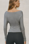 Back view of model posing in soft and lightweight shadow modal Ruched Asymmetrical Long Sleeve top with fitted sleeves, a relaxed asymmetrical hemline and a flattering ruched side detail.