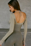 Back view of model posing in the fitted summit flexrib Scoop Corset Long Sleeve with a low scoop back, adjustable ties at the neck, and thumbholes in the mesh sleeves