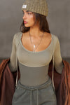 Front view of model posing in the fitted summit flexrib Scoop Corset Long Sleeve with a scoop neckline, adjustable ties at the neck, and thumbholes in the mesh sleeves