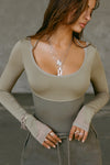 Front view of model posing in the fitted summit flexrib Scoop Corset Long Sleeve with a scoop neckline, adjustable ties at the neck, and thumbholes in the mesh sleeves