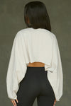 Back view of model posing in the cropped relaxed fit fog cotton slouchy crop long sleeve top with a crew neckline, dropped shoulders and oversized sleeves