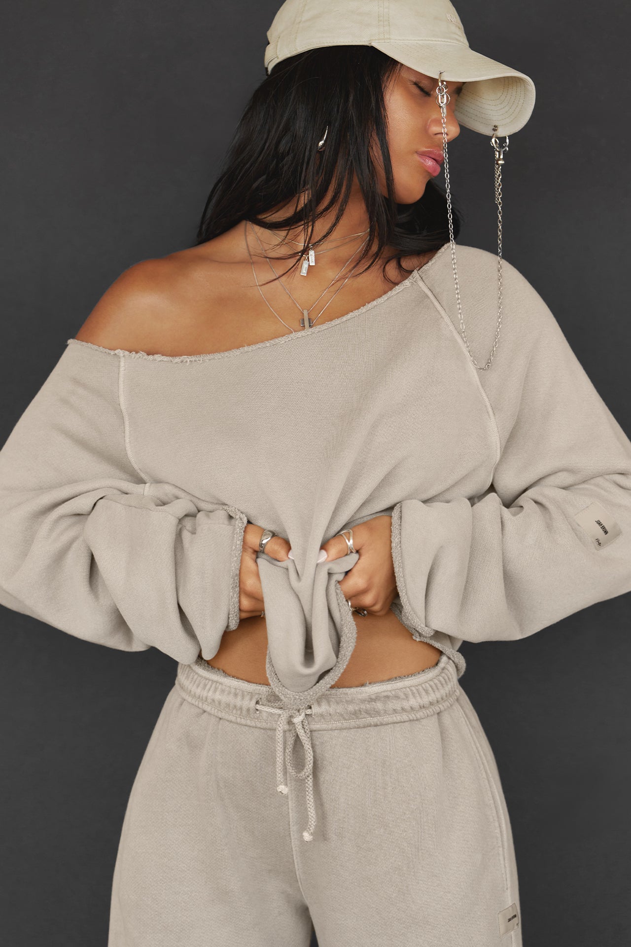 Front view of model posing in the oversized sand french terry Slouchy Pullover Sweatshirt with a wide, off-the-shoulder neckline and a JOAH BROWN logo patch on the right sleeve