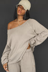 Front view of model posing in the oversized sand french terry Slouchy Pullover Sweatshirt with a wide, off-the-shoulder neckline and a JOAH BROWN logo patch on the right sleeve