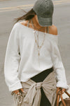 Front view of model posing outside in the street wearing the oversized pearl grey french terry Slouchy Pullover Sweatshirt with a wide, off-the-shoulder neckline and a JOAH BROWN logo patch on the right sleeve